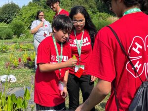 STEM Ambassadors gather around of a one STEM Ambassador holding a frog