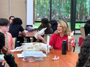 A woman teaches STEM Ambassadors she is holding fossils in her hands
